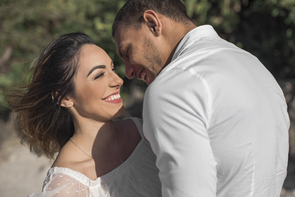 Melhor fotógrafo Nossa Casa Estúdio ensaio fotográfico profissional de casal na cidade de Niterói Rio de janeiro para pré wedding e casamento na praia de adão e eva ao por do sol na areia e mar com noivos/namorados vestidos de branco. Maquiagem noiva