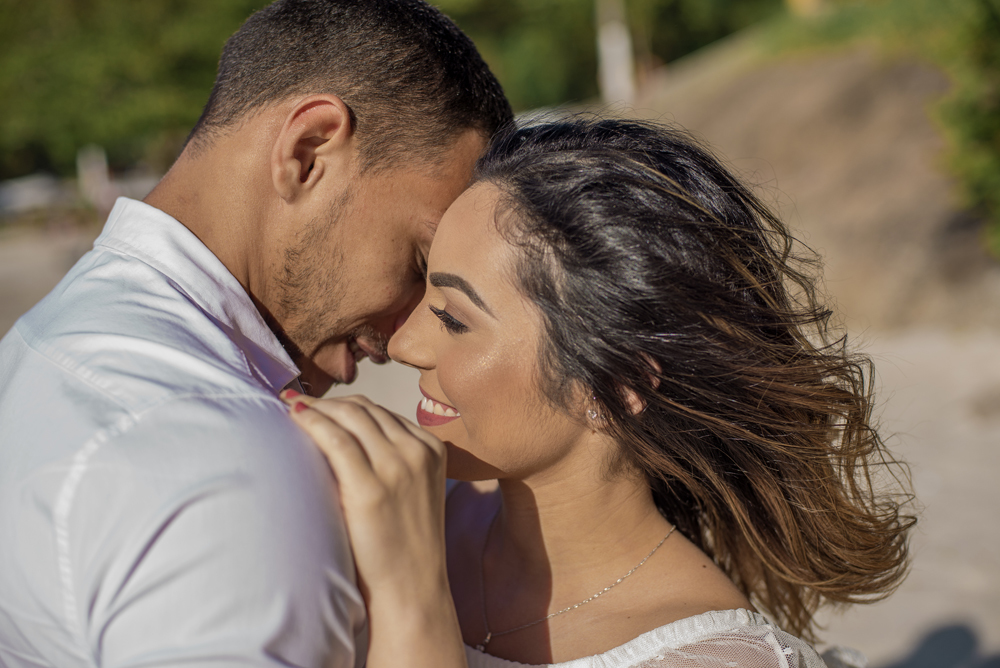 Melhor fotógrafo Nossa Casa Estúdio ensaio fotográfico profissional de casal na cidade de Niterói Rio de janeiro para pré wedding e casamento na praia de adão e eva ao por do sol na areia e mar com noivos/namorados vestidos de branco. Maquiagem noiva