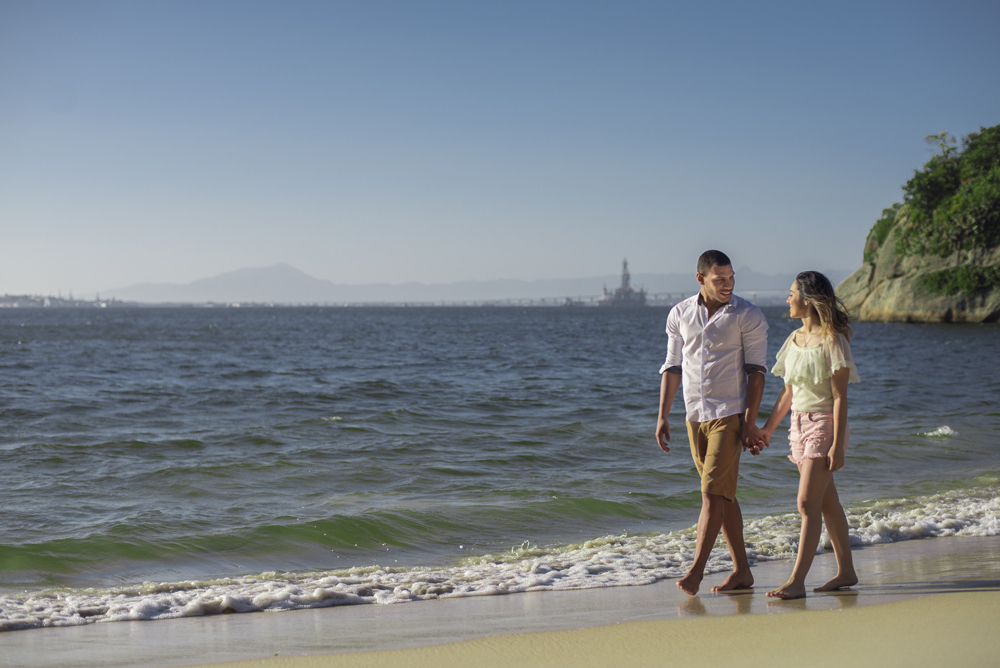 Melhor fotógrafo Nossa Casa Estúdio ensaio fotográfico profissional de casal na cidade de Niterói Rio de janeiro para pré wedding e casamento na praia de adão e eva ao por do sol na areia e mar com noivos/namorados vestidos de branco. Maquiagem noiva