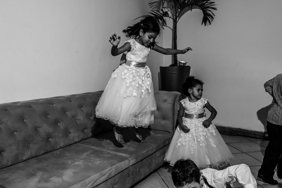 crianças brincando e pulando de vestido branco pulando em sofá na decoração da festa de casamento pista de dança ao som do dj a noite fotografia de casamento criatividade no rio de janeiro solar imperial em Niterói 