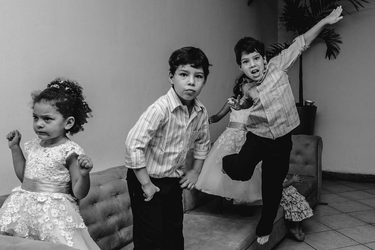 crianças brincando e pulando de vestido branco pulando em sofá na decoração da festa de casamento pista de dança ao som do dj a noite fotografia de casamento criatividade no rio de janeiro solar imperial em Niterói 