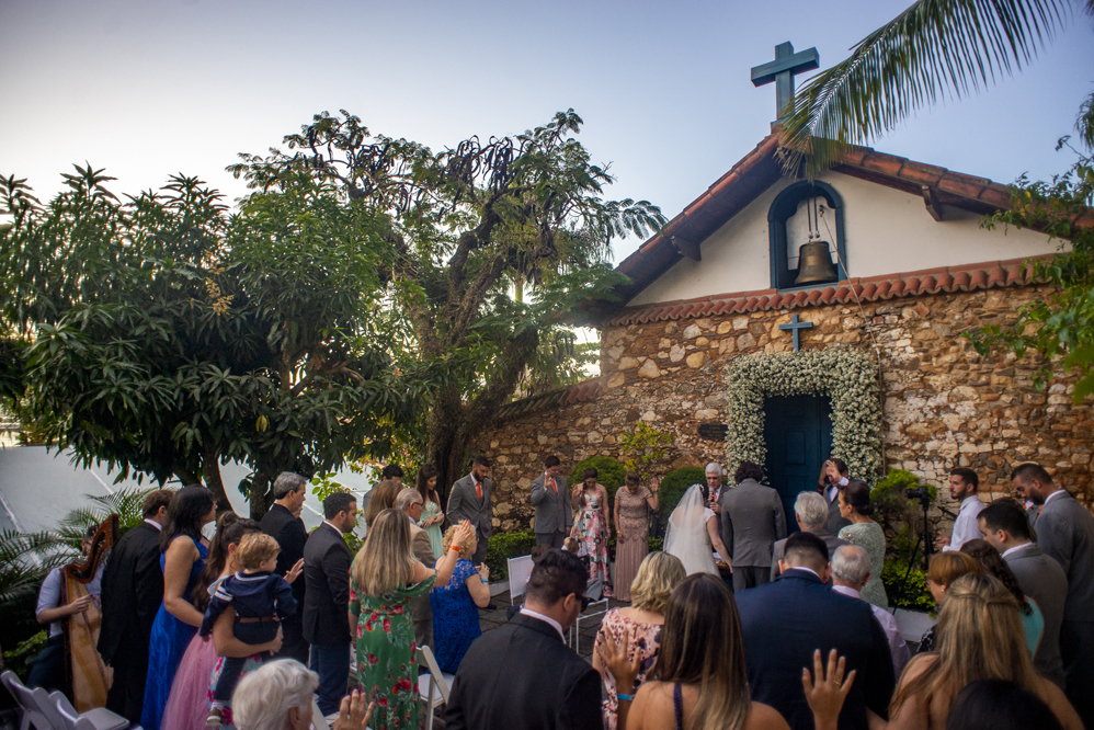 Nossa Casa Estúdio Fotografia de casamento em Niterói Rio de Janeiro Búzios Cabo Frio Hotel Atlântico Búzios noiva em cerimônia de casamento com noivo de gravata laranja  com vestido branco no por do Sol frente  mar para a praia com decoração rústica