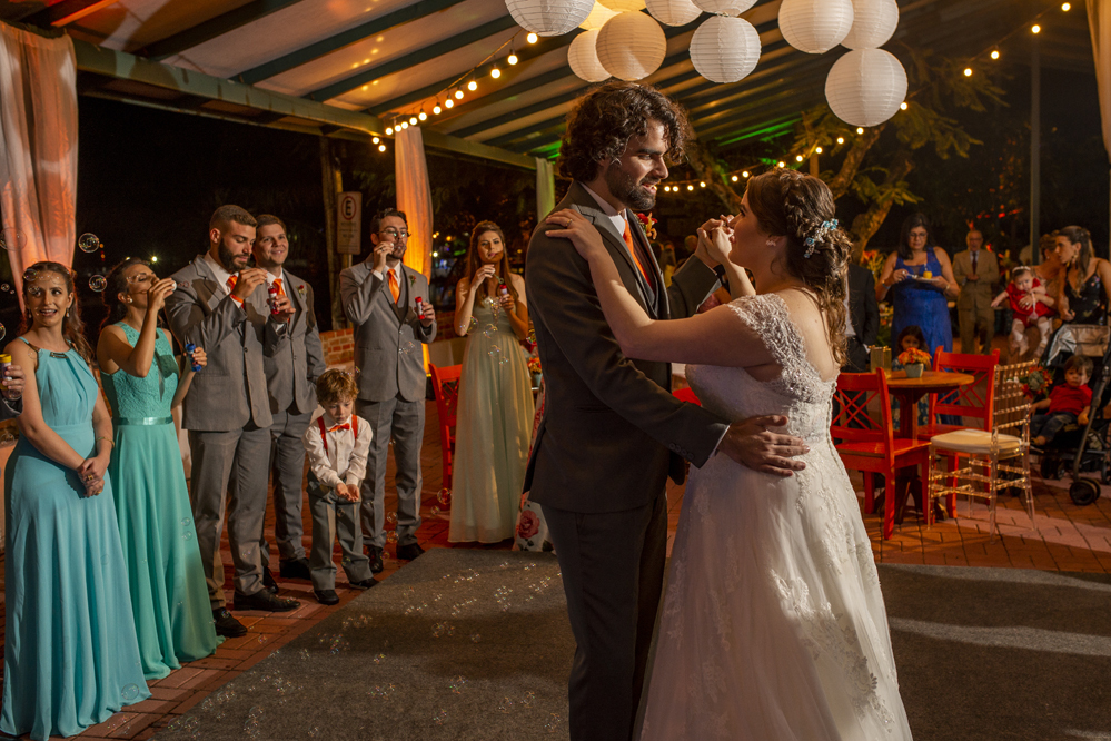 Nossa Casa Estúdio Fotografia profissional de casamento em Niterói Búzios Cabo Frio Rio de Janeiro em Hotel Atlântico Búzios casal de noivos dançando com vestido branco e terno com padrinhos madrinhas e convidados assistindo em festa na pista de dança