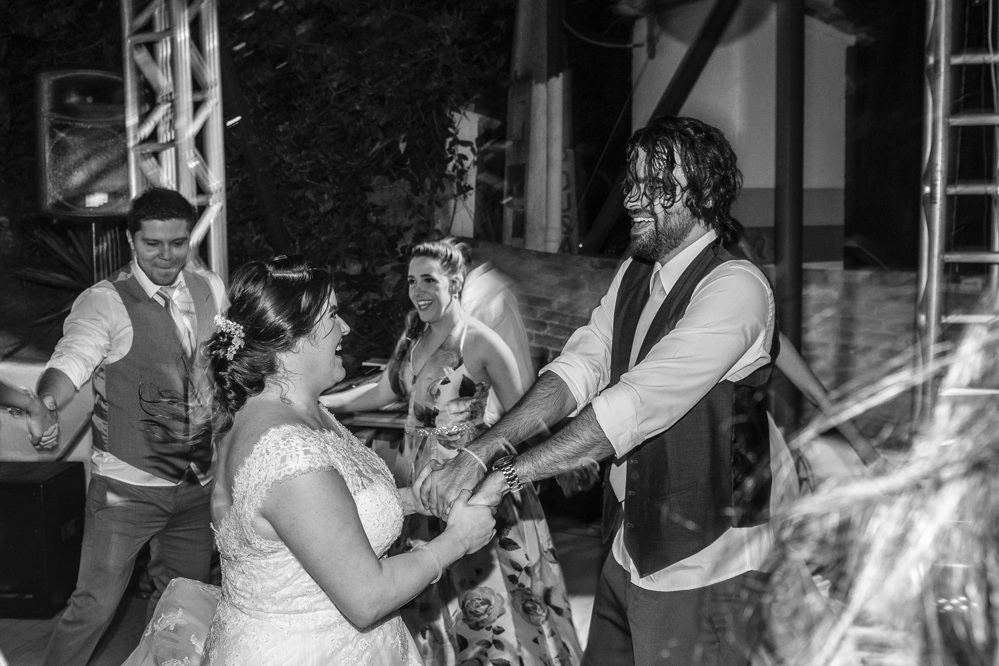Nossa Casa Estúdio Fotografia profissional de casamento em Niterói Búzios Cabo Frio Rio de Janeiro em Hotel Atlântico Búzios casal de noivos dançando com vestido branco e terno com padrinhos madrinhas e convidados assistindo em festa na pista de dança