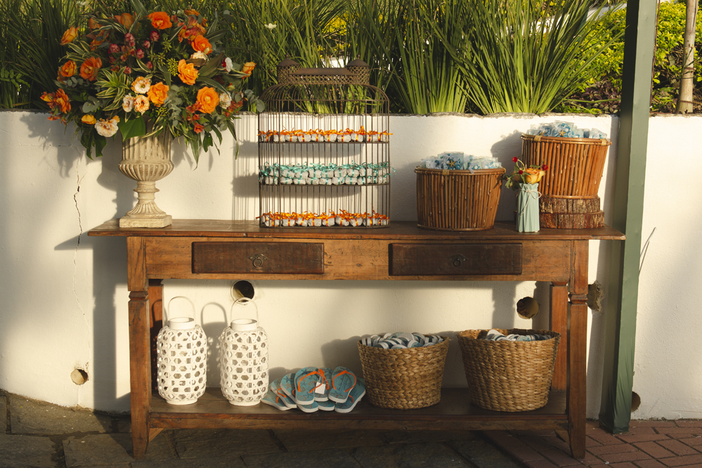 Nossa Casa Estúdio Fotografia de casamento profissional em Búzios Niterói Rio de Janeiro Decoração Rústica em festa no Hotel Atlântico Búzios para convidados casal de noivos com dicas e tendências a beira mar de dia no por do Sol laranja e docinhos