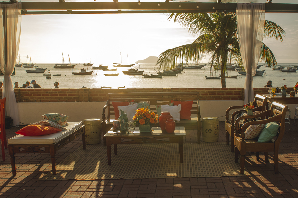 Nossa Casa Estúdio Fotografia de casamento profissional em Búzios Niterói Rio de Janeiro Decoração Rústica em festa no Hotel Atlântico Búzios para convidados casal de noivos com dicas e tendências a beira mar de dia no por do Sol laranja e docinhos
