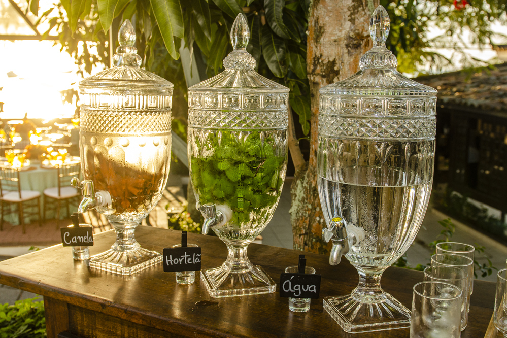 Nossa Casa Estúdio Fotografia de casamento profissional em Búzios Niterói Rio de Janeiro Decoração Rústica em festa no Hotel Atlântico Búzios para convidados casal de noivos com dicas e tendências a beira mar de dia no por do Sol laranja e docinhos