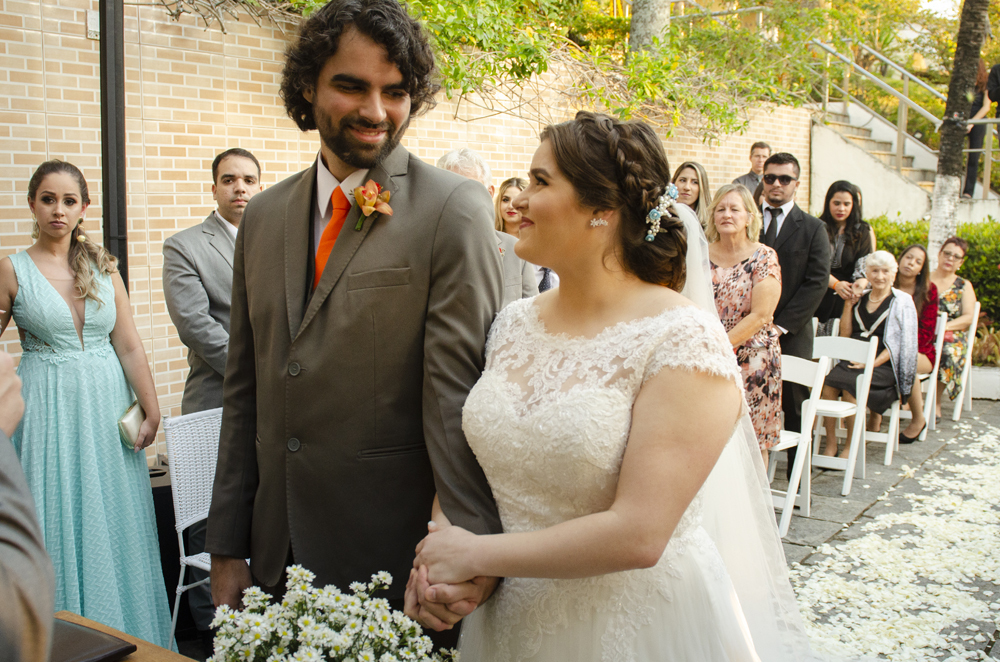 Nossa Casa Estúdio Fotografia de casamento em Niterói Rio de Janeiro Búzios Cabo Frio Hotel Atlântico Búzios noiva em cerimônia de casamento com noivo de gravata laranja  com vestido branco no por do Sol frente  mar para a praia com decoração rústica