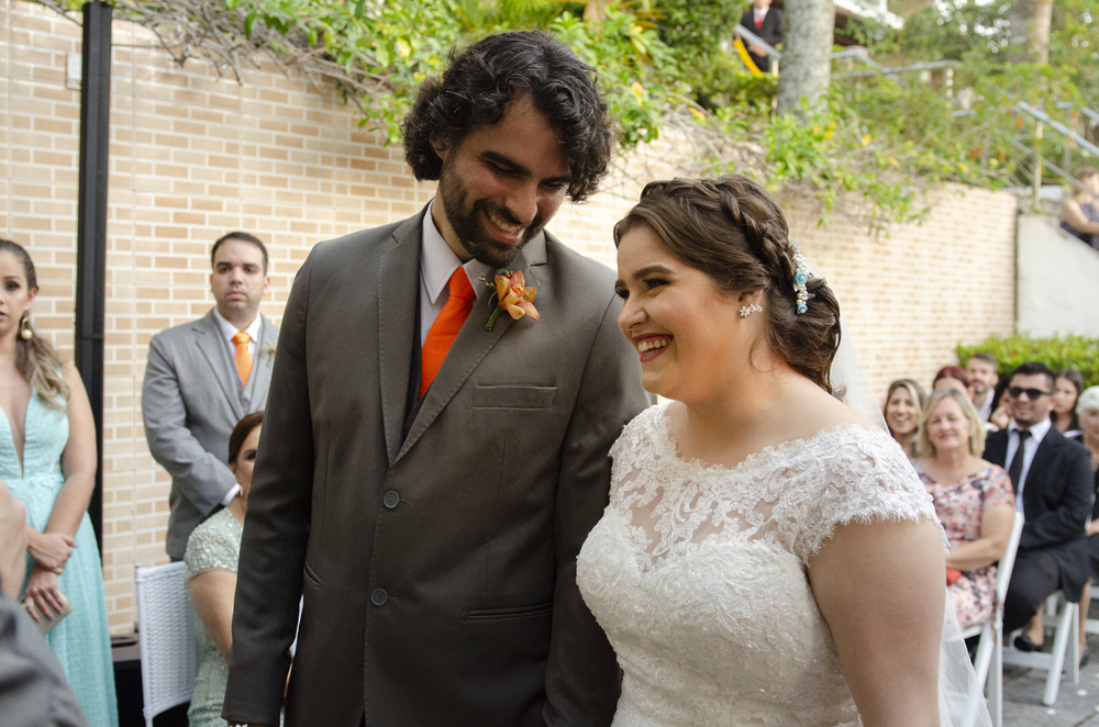 Nossa Casa Estúdio Fotografia de casamento em Niterói Rio de Janeiro Búzios Cabo Frio Hotel Atlântico Búzios noiva em cerimônia de casamento com noivo de gravata laranja  com vestido branco no por do Sol frente  mar para a praia com decoração rústica