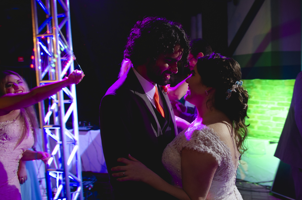 Nossa Casa Estúdio Fotografia profissional de casamento em Niterói Búzios Cabo Frio Rio de Janeiro em Hotel Atlântico Búzios casal de noivos dançando com vestido branco e terno com padrinhos madrinhas e convidados assistindo em festa na pista de dança