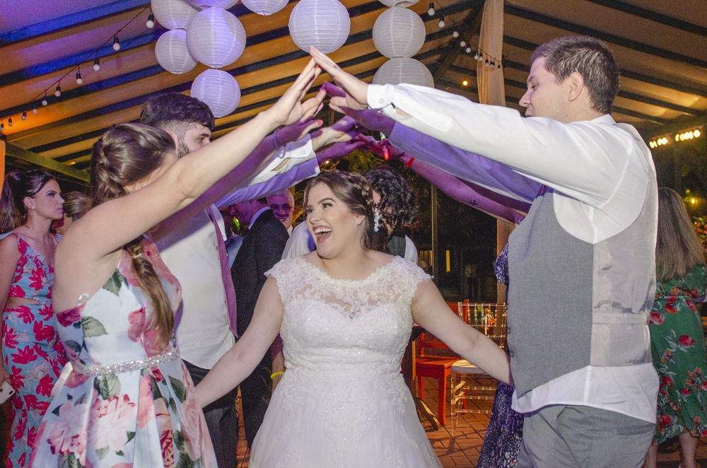 Nossa Casa Estúdio Fotografia profissional de casamento em Niterói Búzios Cabo Frio Rio de Janeiro em Hotel Atlântico Búzios casal de noivos dançando com vestido branco e terno com padrinhos madrinhas e convidados assistindo em festa na pista de dança