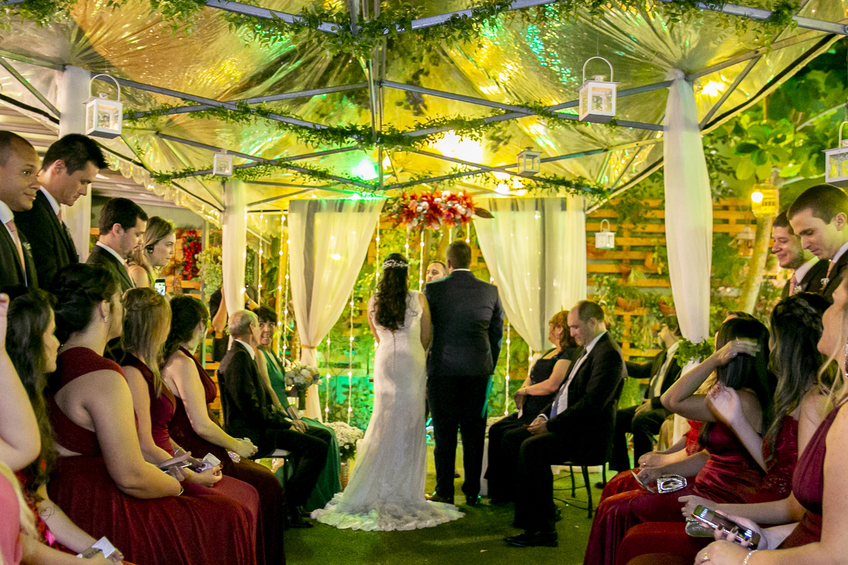 Nossa Casa Estúdio fotografia profissional de casamento em Niterói e Rio de Janeiro casal no altar com decoração rústica vestido de noiva branco com terno do noivo azul e padrinhos e madrinhas de vestido vinho cerimônia de casamento