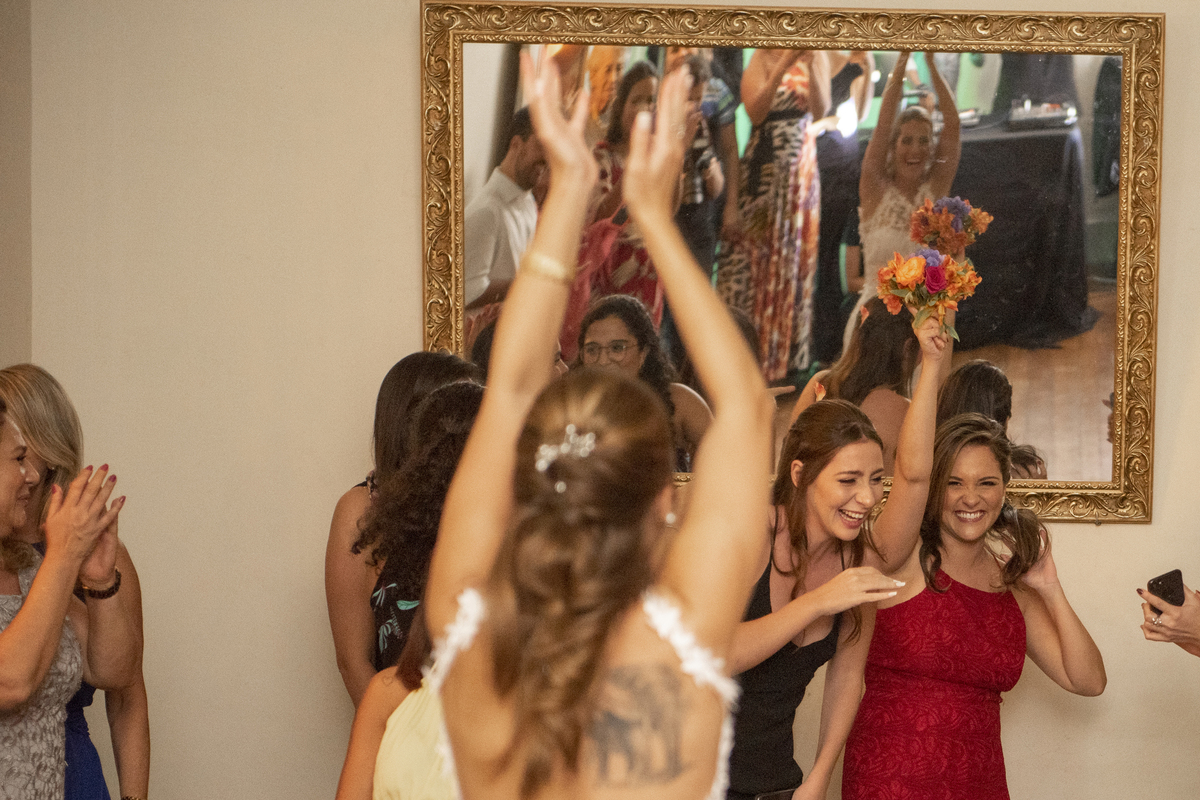 Casal de noivos dançando na pista de dança em dia do casamento com vestido branco e camisa para o noivo em Solar das Palmeiras no bairro de Botafogo convidados no momento do buque da noiva