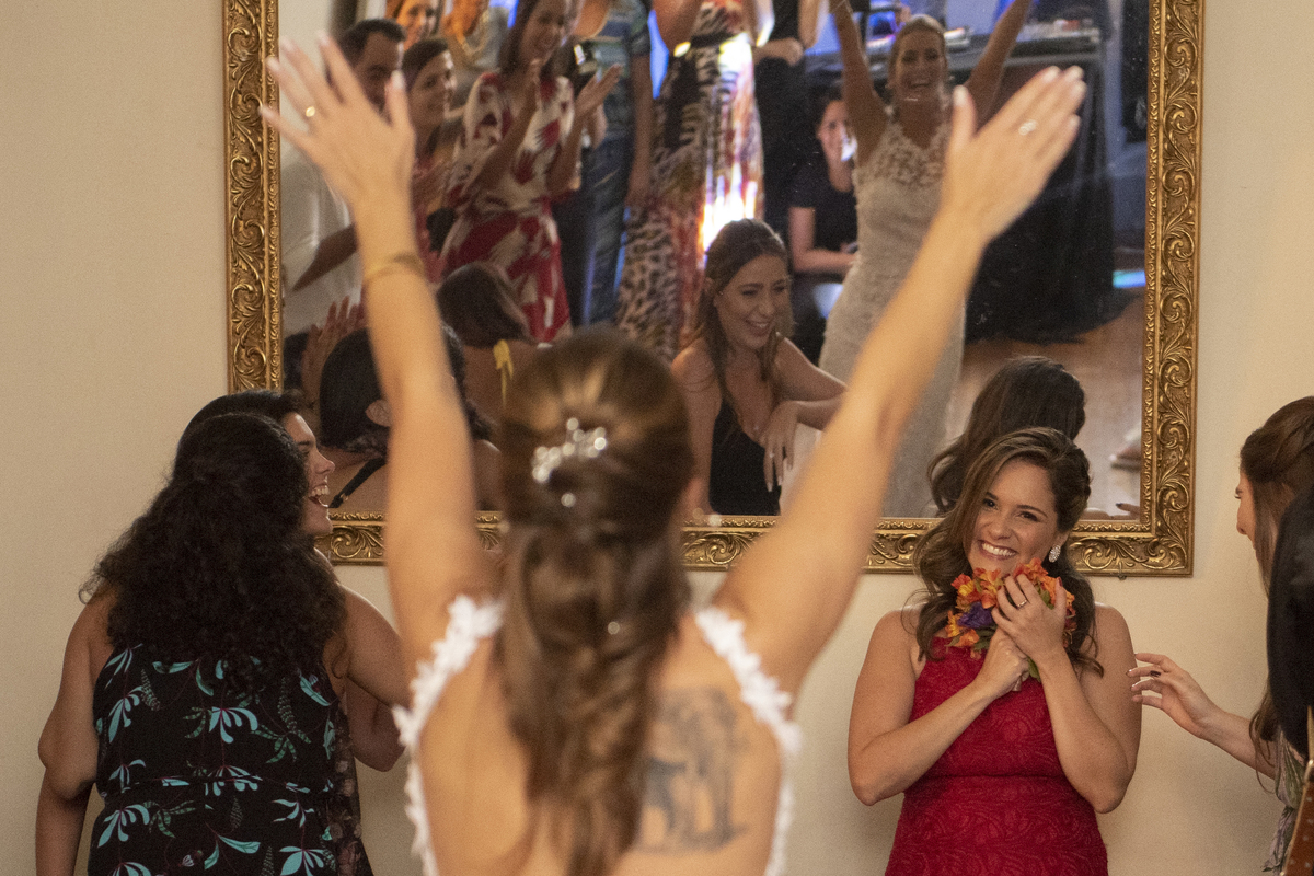 Casal de noivos dançando na pista de dança em dia do casamento com vestido branco e camisa para o noivo em Solar das Palmeiras no bairro de Botafogo convidados no momento do buque da noiva