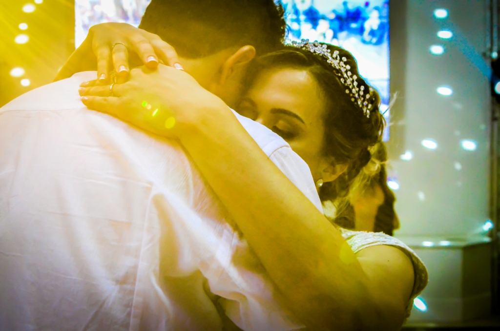 Festa de casamento noivos com luz amarela dançando na pista agarradinhos para comemorar o amor juntos união dos noivos e da nova família, grinalda, pista de dança