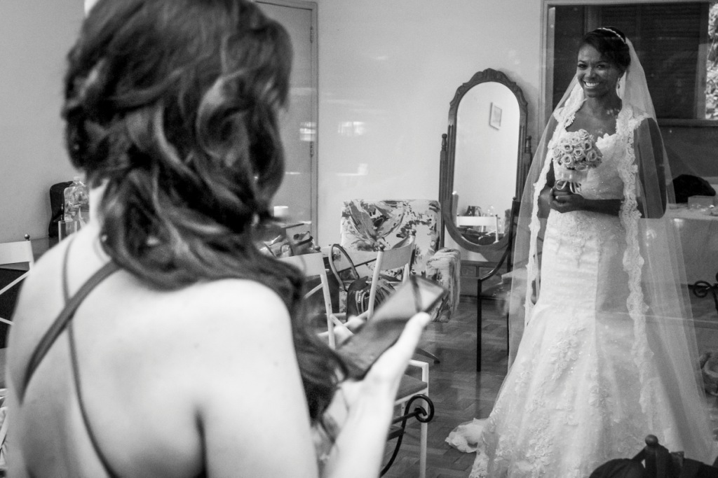 Noiva em making of com as amigas em fotografia preta e branca tirada por Gilson Freitas fotógrafo de casamentos profissional em Niterói e Rio de Janeiro  no making of madrinhas se preparando para a cerimônia e festa com vestido branco todas olhando 