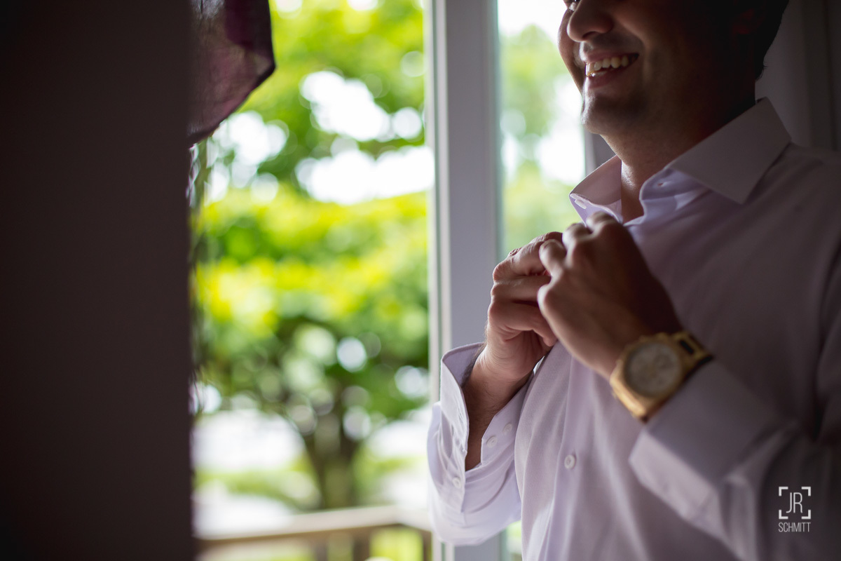 noivo abotoando a gola da camisa com relógio dourado