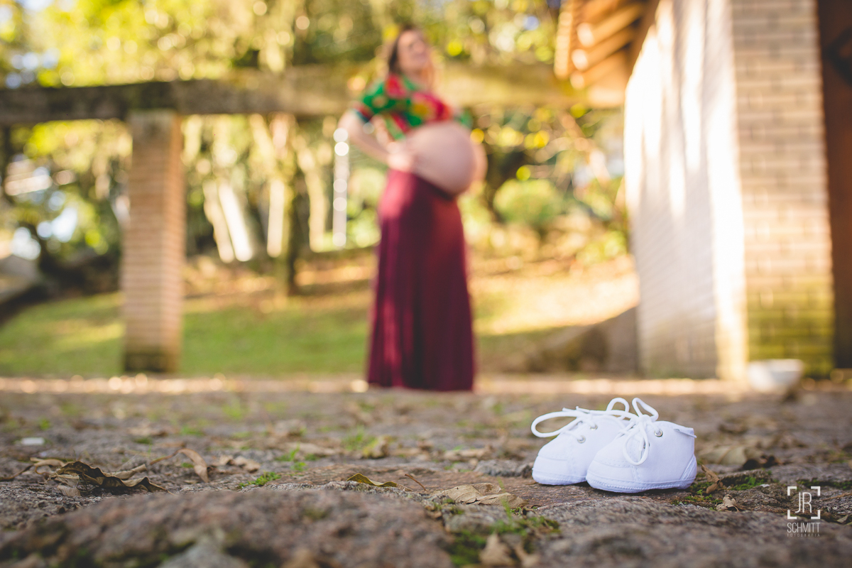 Sapatinho do bebê com gestante ao fundo