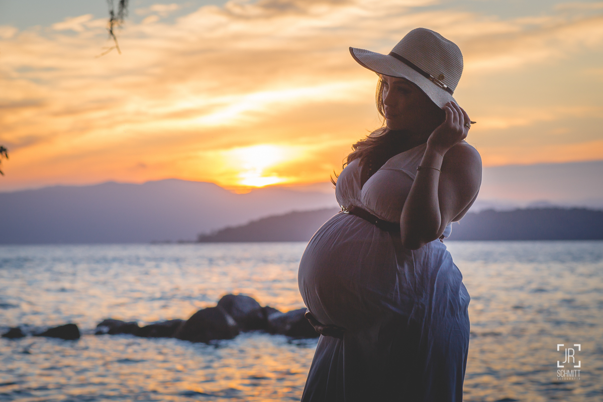 Gestante de chapéu no pôr-do-sol contra-luz