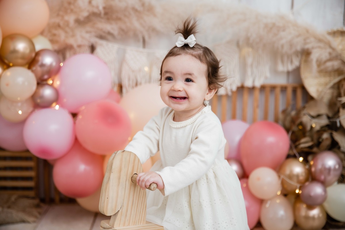 Bebe no cavalinho de balanço cenário smash the cake boho chic sorrindo