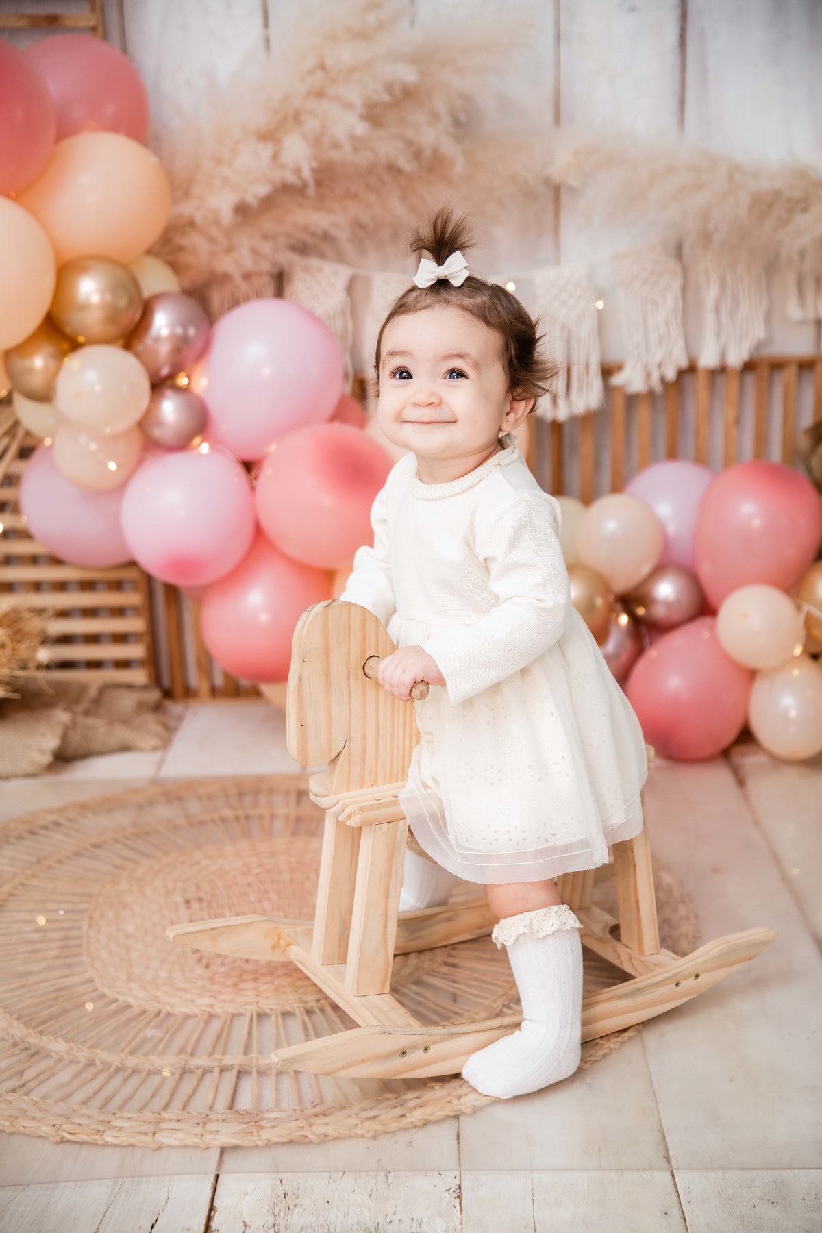 Bebe no cavalinho de balanço cenário smash the cake boho chic sorrindo em pé