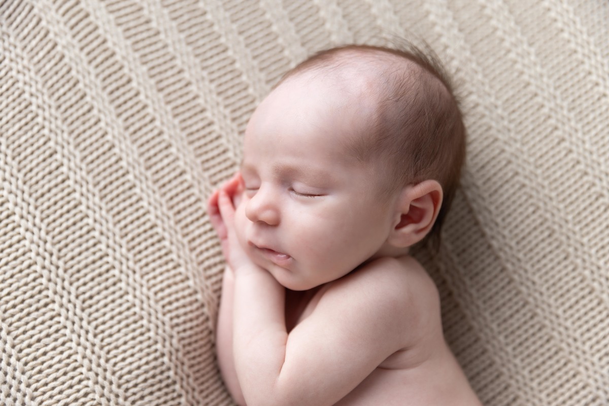 bebe deitado com mão de ladinho no pufe