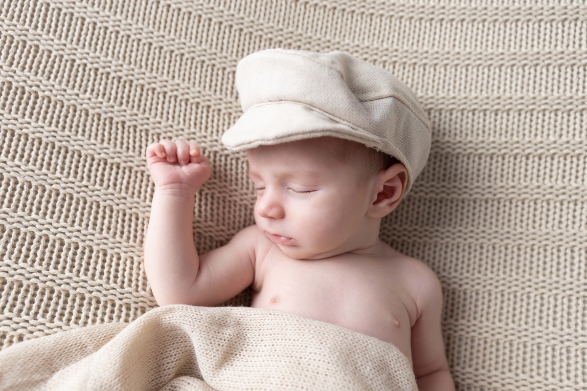 bebe deitado com boina no pufe