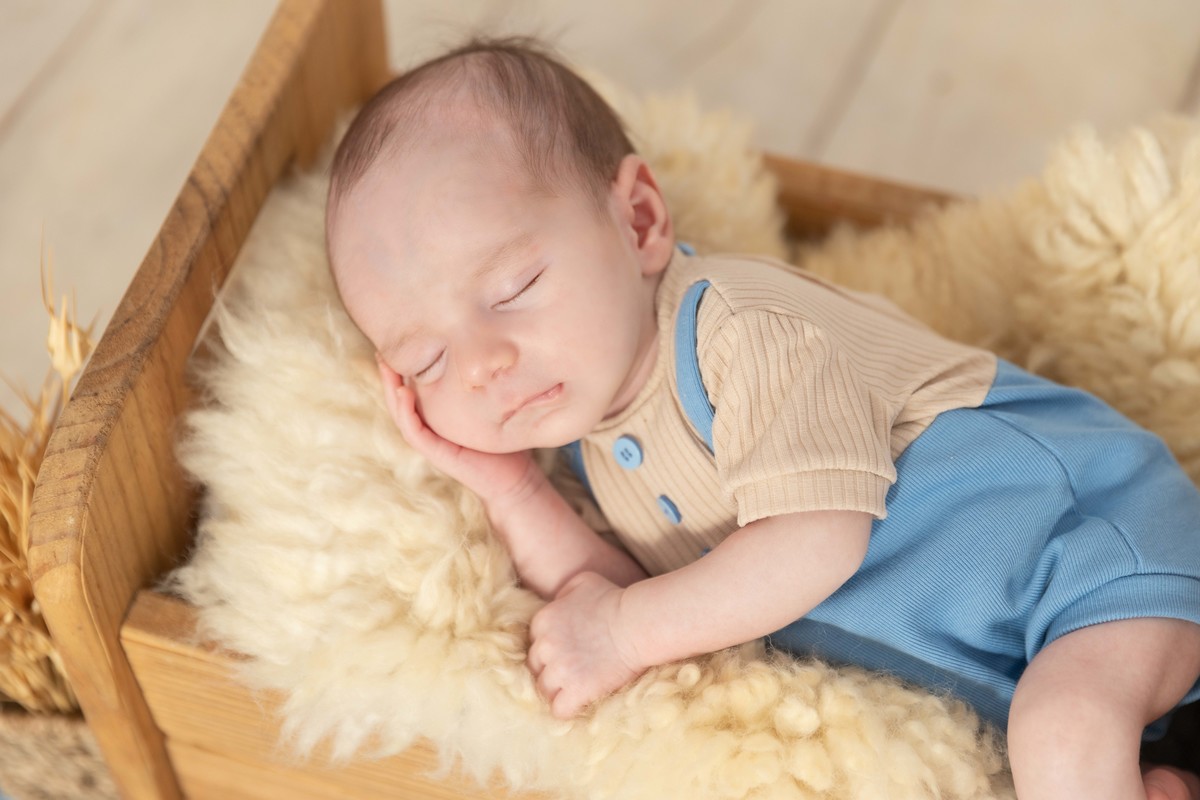 bebe deitado na cama de madeira zoom