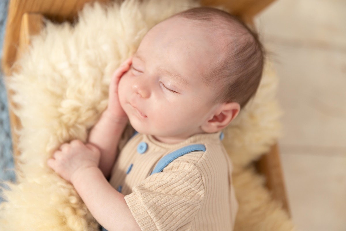 bebe deitado na cama de madeira de lado
