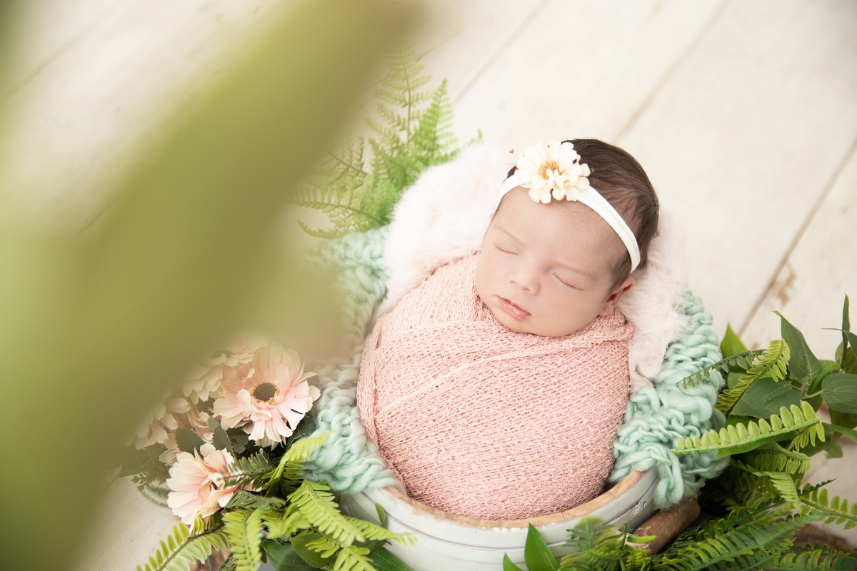 bebe enroladinha no balde com flores de lado