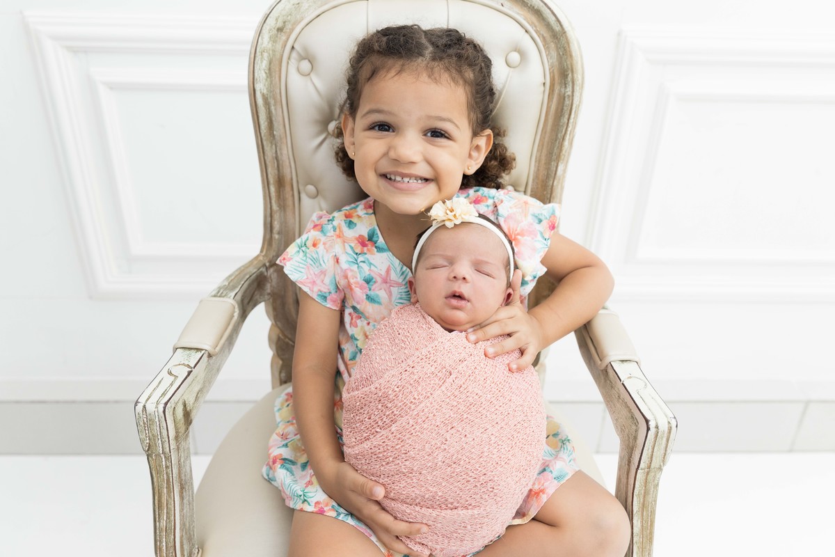 bebe enroladinha no colo da irmã