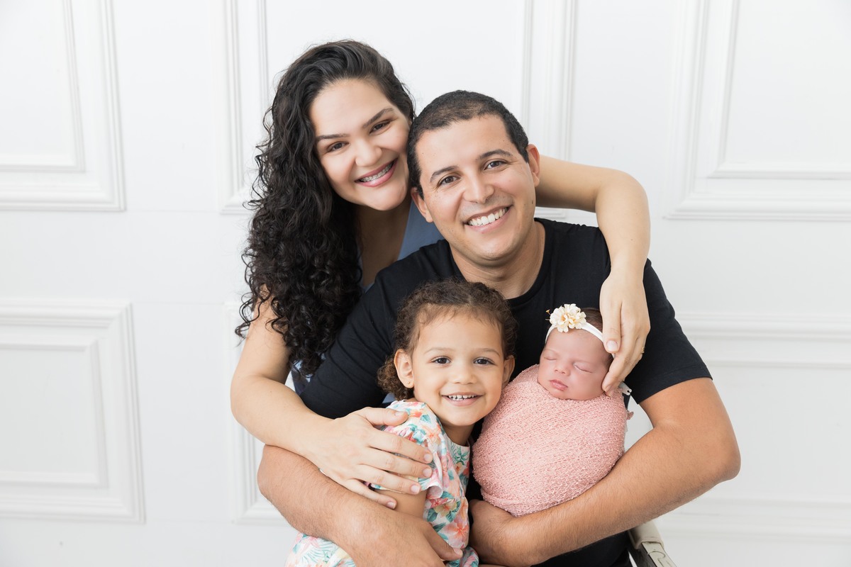 bebe enroladinha no colo dos pais com irmã