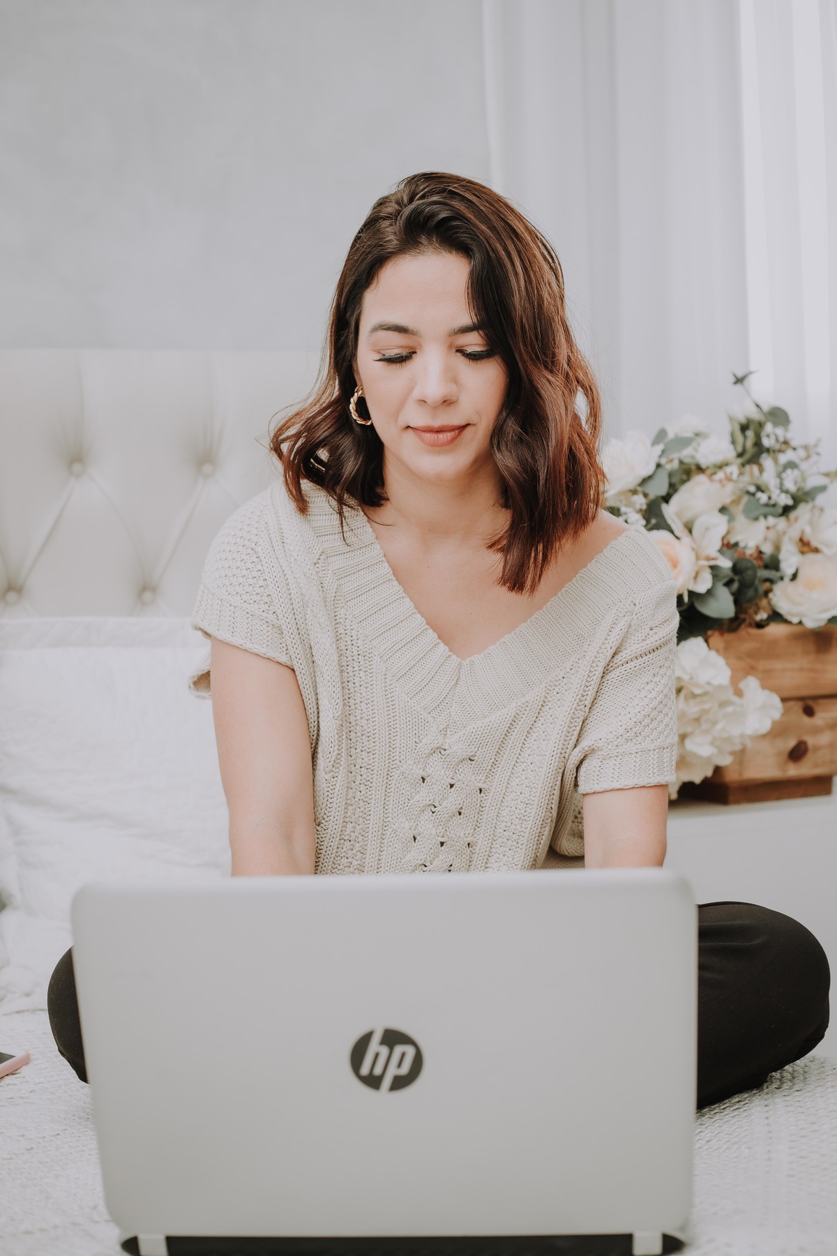 mulher blaser azul Coach no computador sentada na cama