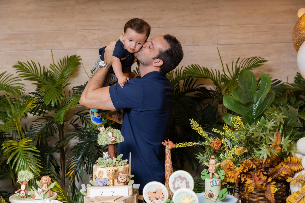 bebe no colo do pai na mesa do bolo tema safari beijo do pai
