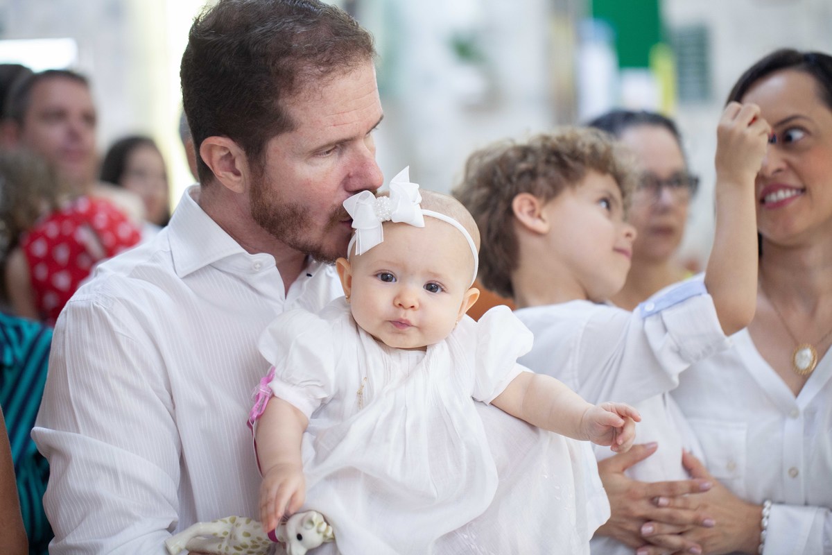 Papai da bebê dando beijo em seu rostinho durante o batismo