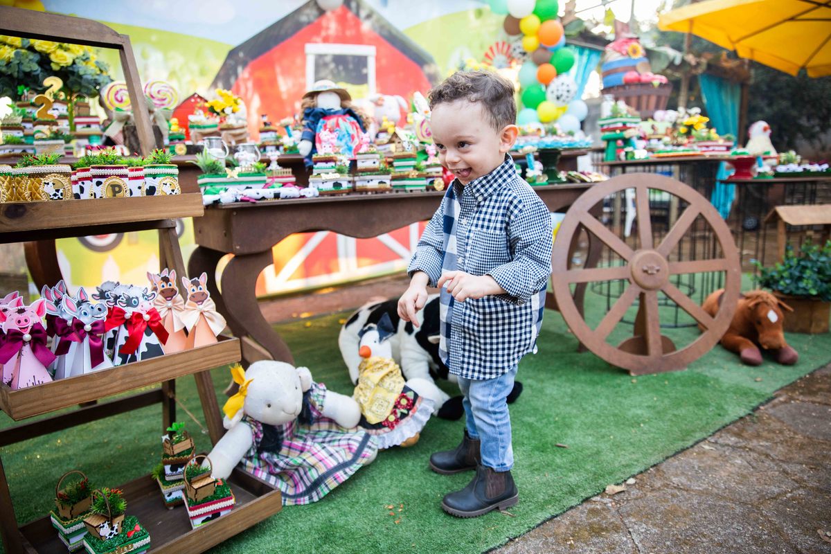 Aniversariante fazendo graça com  camisa xadrez  tema fazendinha na roça