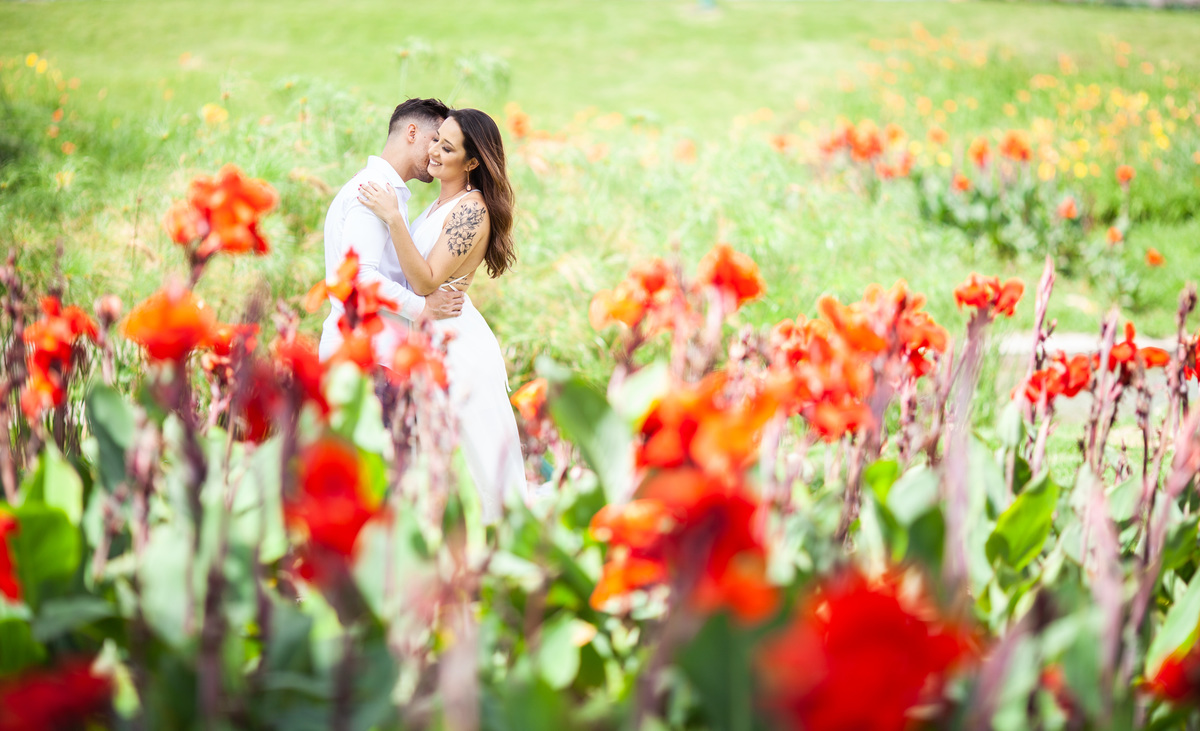 casal no meio de lindas flores vermelhas abraçados sorrindo