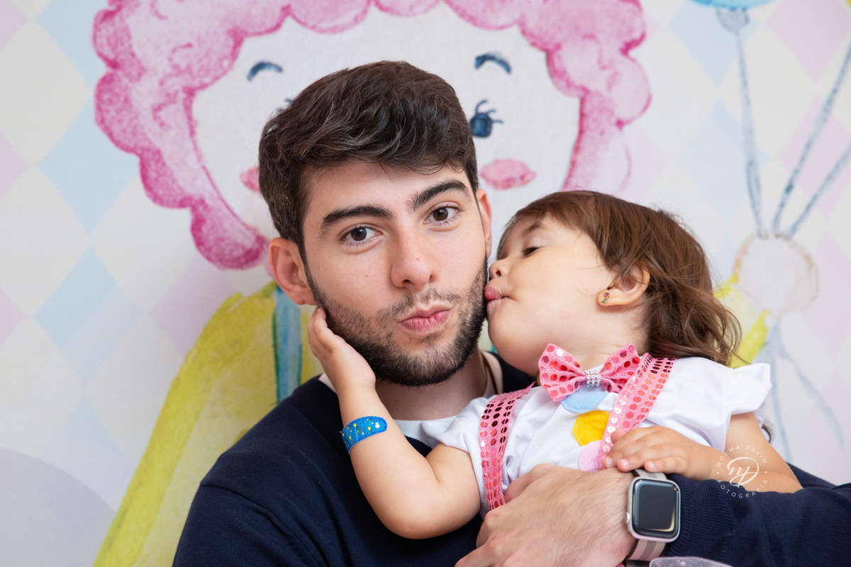 Festa infantil tema circo 2 anos menina rosa no colo do tio beijando o titio