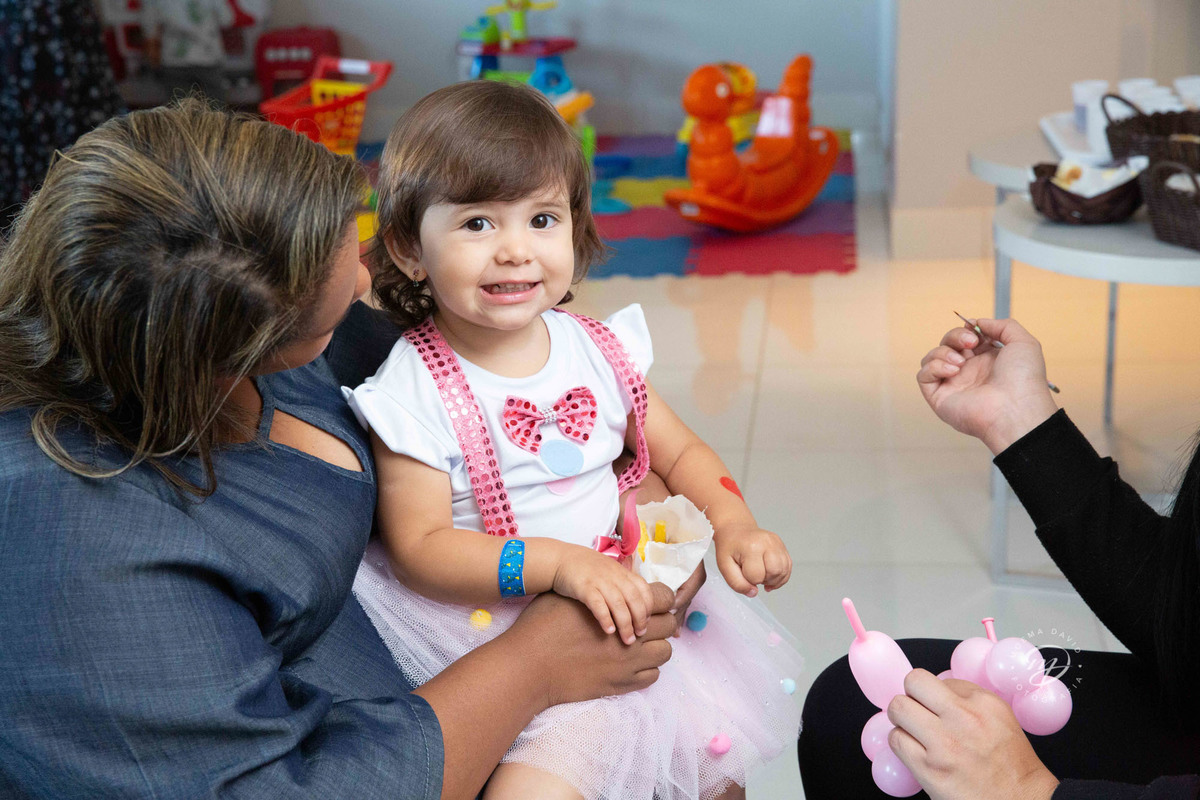 Festa infantil tema circo 2 anos menina rosa no colo da babá fazendo pinturinha
