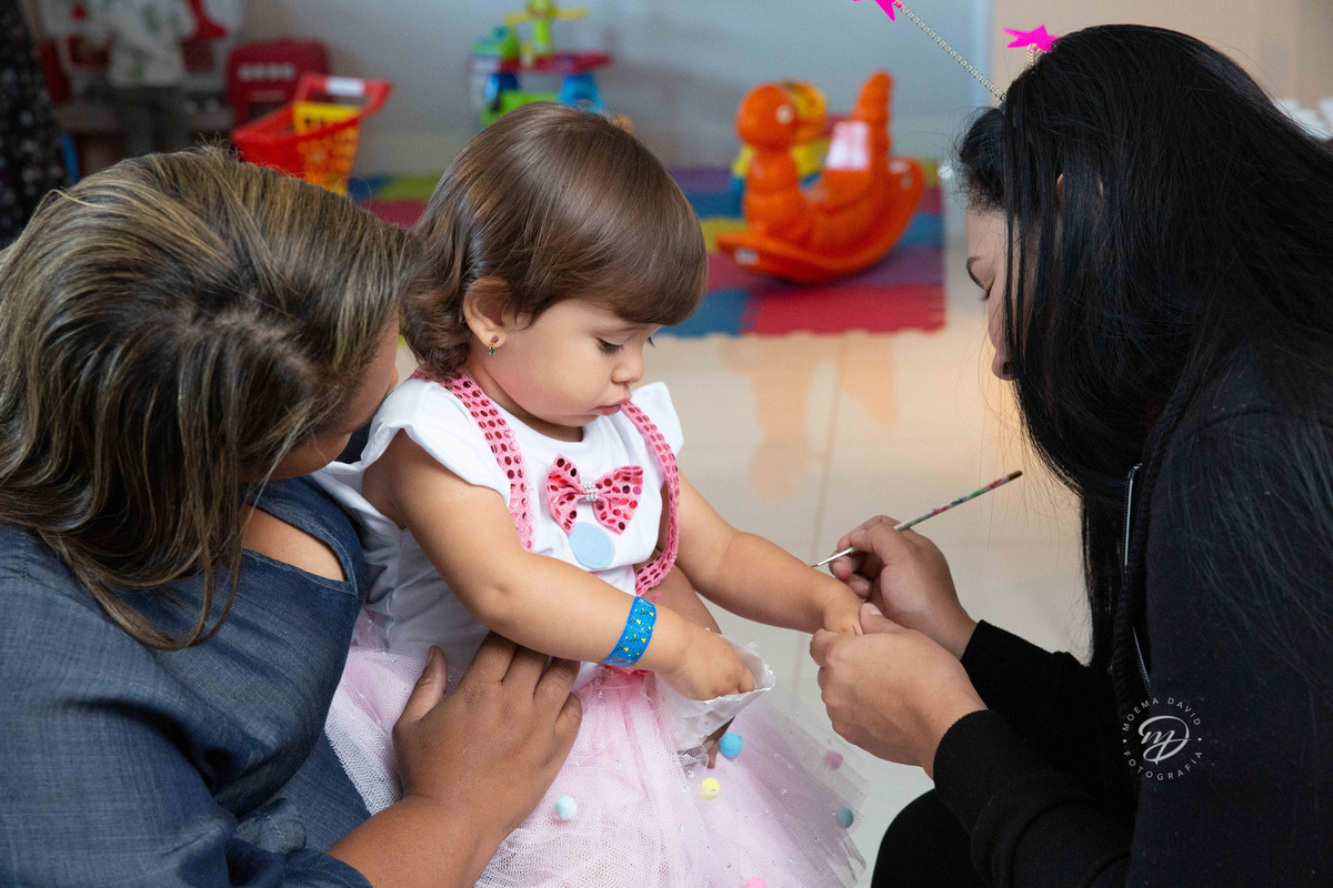 Festa infantil tema circo 2 anos menina rosa no colo da babá fazendo pinturinha
