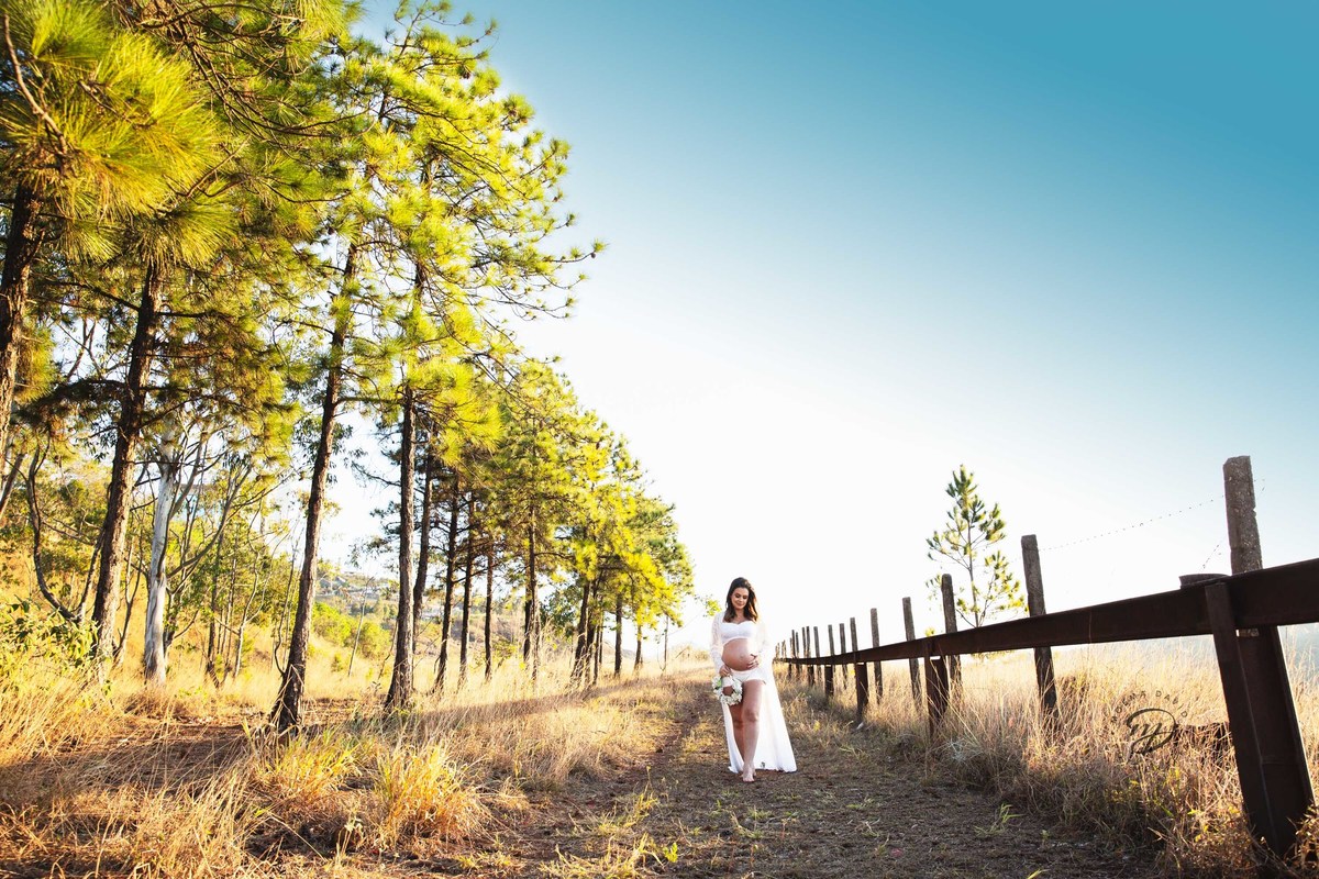 Gestante mamãe esperando bebe que irá nascer segurando barriga vestido branco roupa saia longa  pinheiros sereia coroa de flor