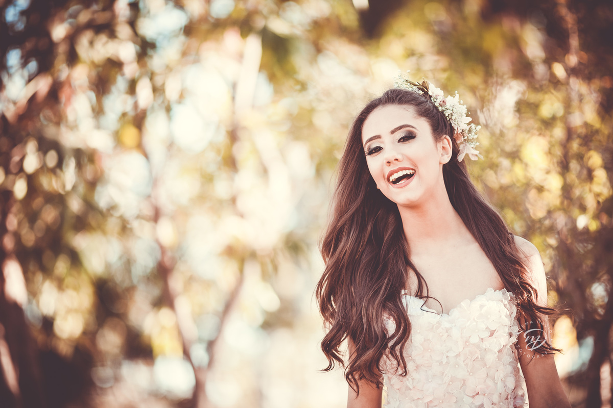 Debutante 15 anos natureza ar livre coroa de flores vestido rosa floral galhos luz natural gargalhada