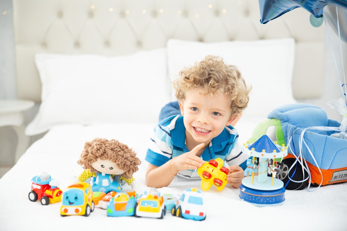 Menino lindo olhos azuis brinquedos carrinhos balões cama trem carrossel