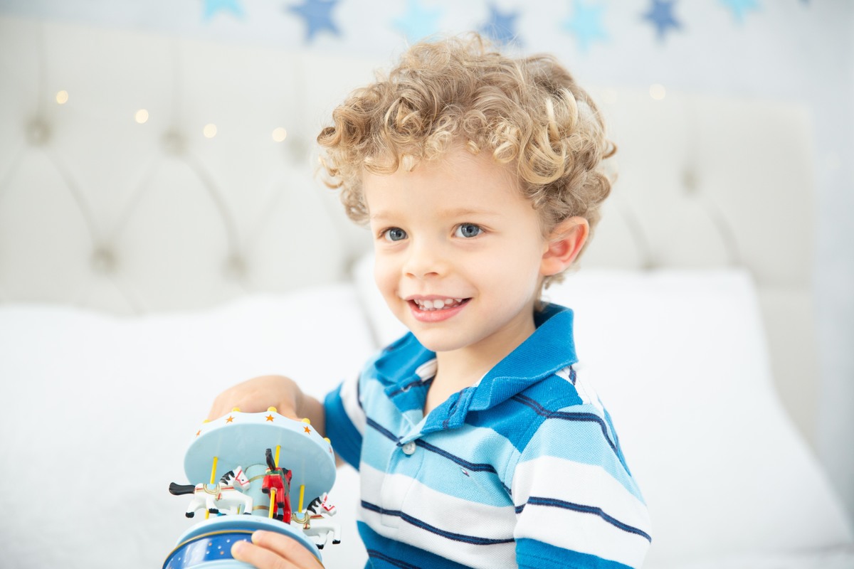 Menino lindo olhos azuis brinquedos carrinhos balões cama trem carrossel estrelas