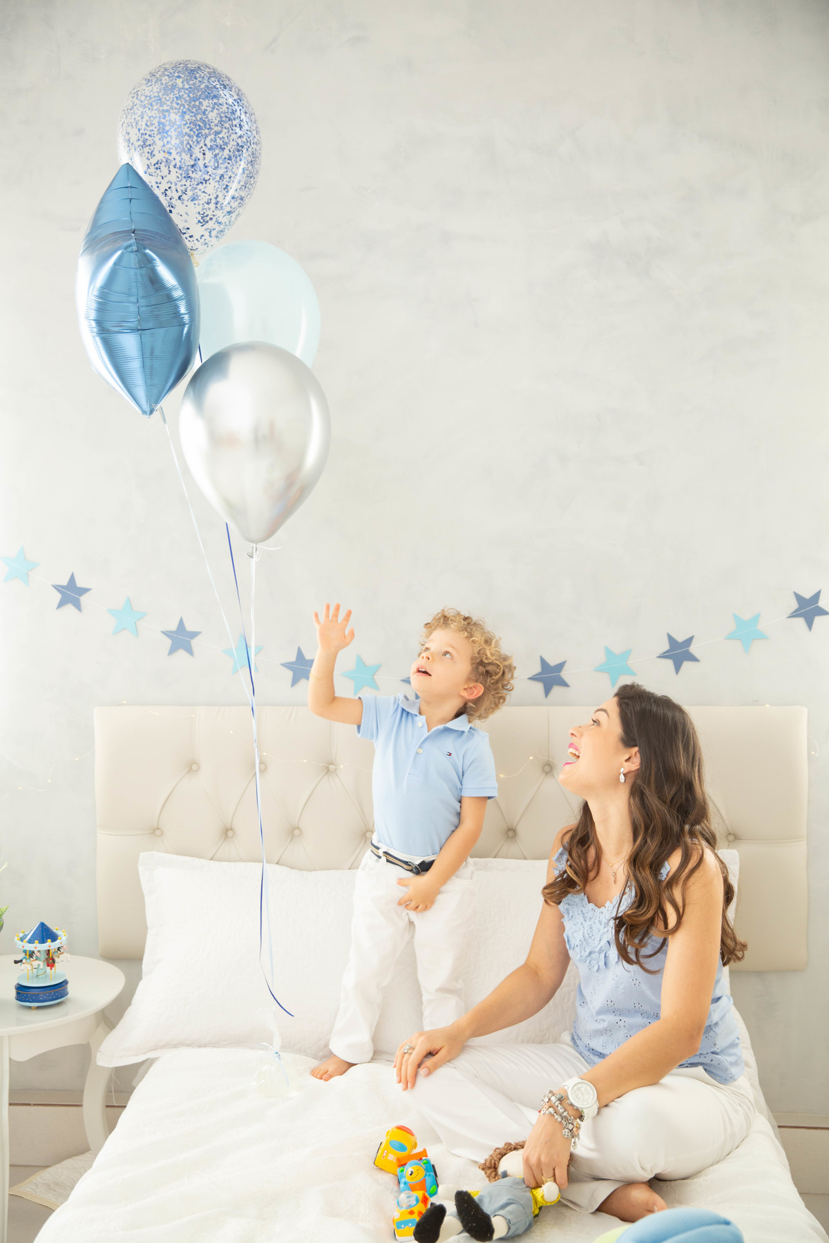 Menino lindo olhos azuis brinquedos carrinhos balões cama trem carrossel estrelas mamae