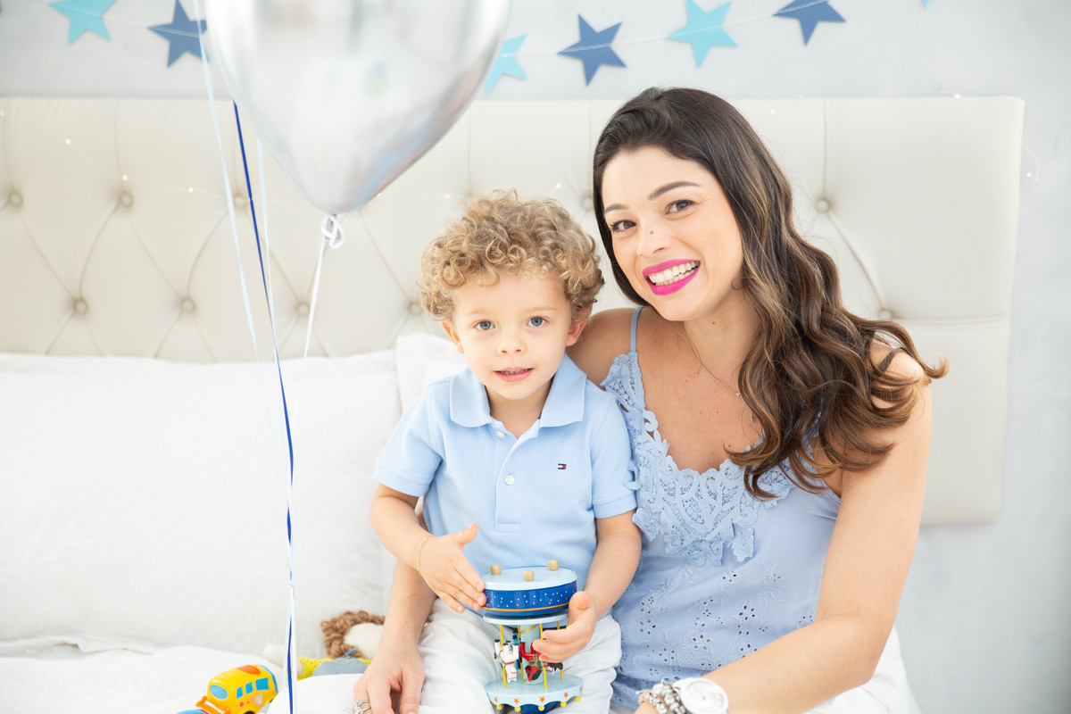 Menino lindo olhos azuis brinquedos carrinhos balões cama trem carrossel colo