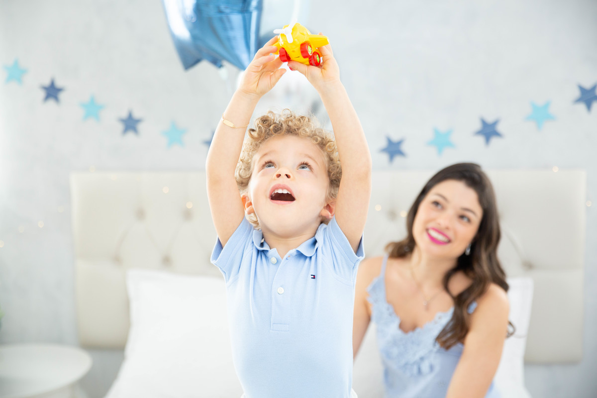 Menino lindo olhos azuis brinquedos carrinhos balões cama trem carrossel céu estrelas
