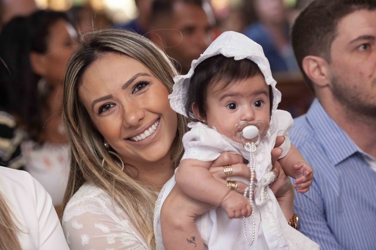 Bebe no colo da madrinha.