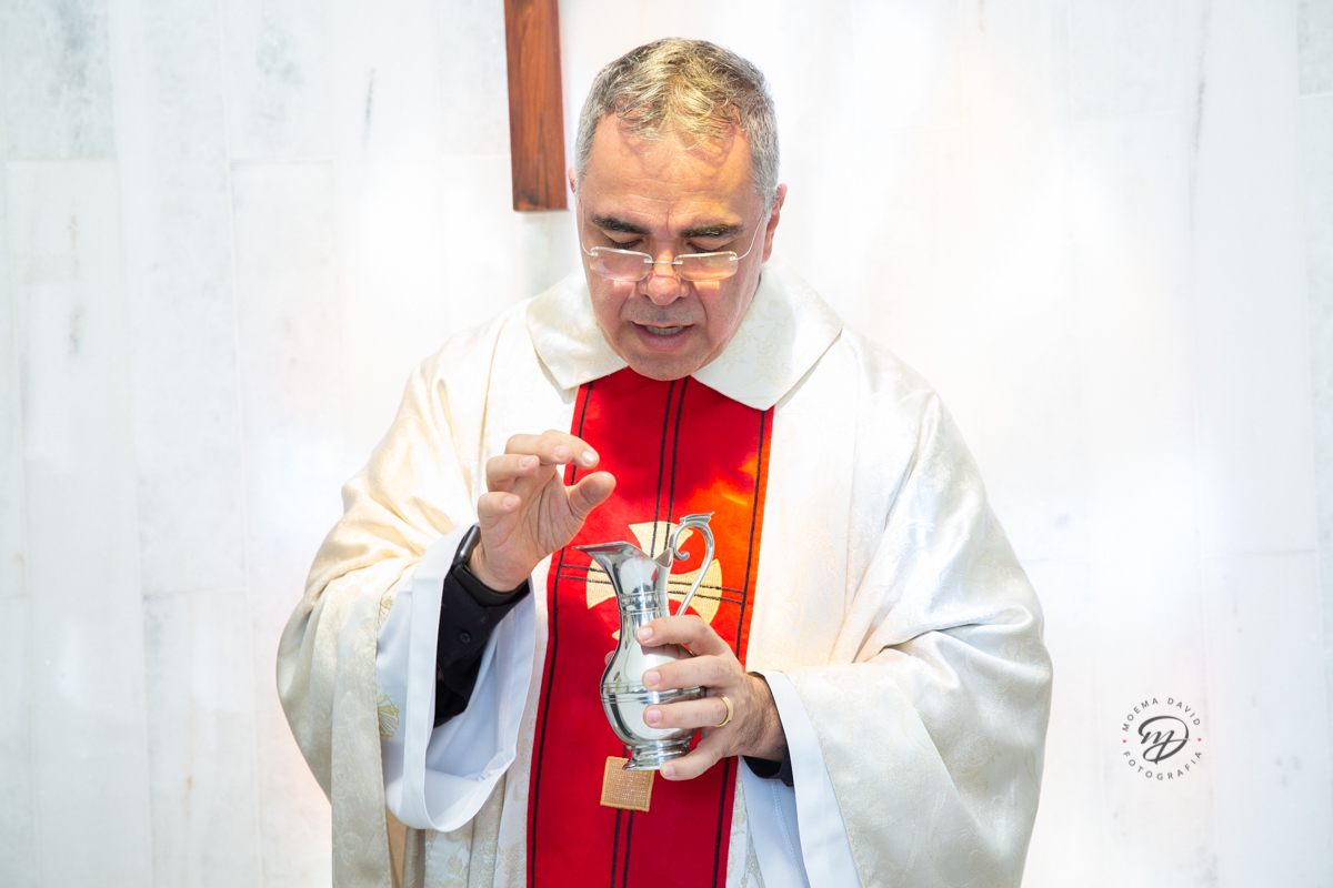 Sacerdote abençoando a água do batismo. 