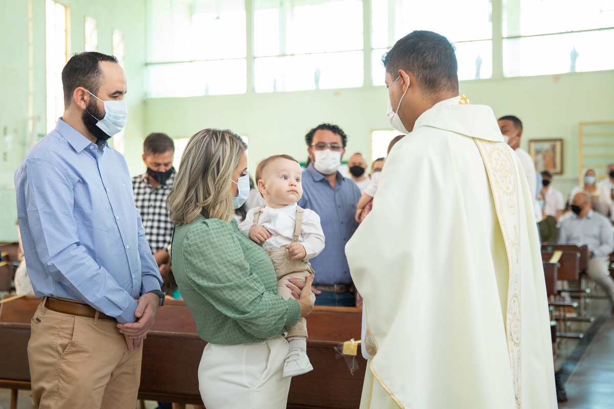 Menino olhando para o padre no colo da mae batizado